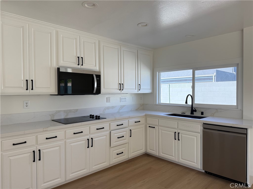 6441 St Paul Circle, Unit A Huntington Beach, CA 92647 - Photo 5 of 13 a kitchen with white cabinets sink and dishwasher