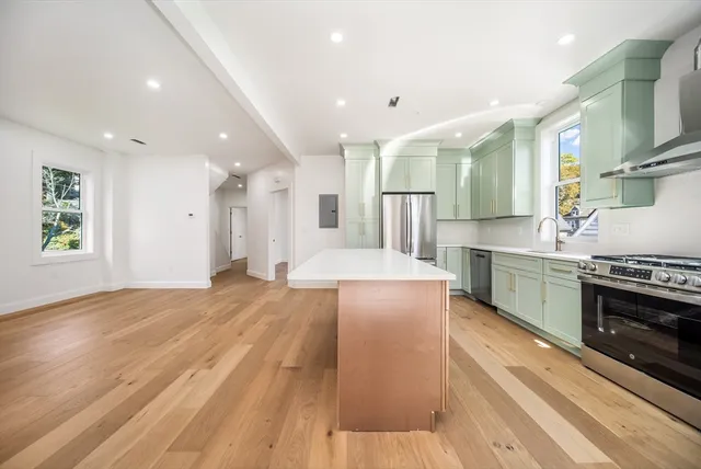 a large kitchen with stainless steel appliances granite countertop a lot of cabinets and wooden floor