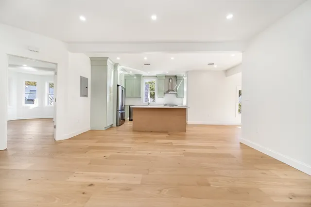 a large kitchen with stainless steel appliances granite countertop a large counter top a wooden floors and a large window