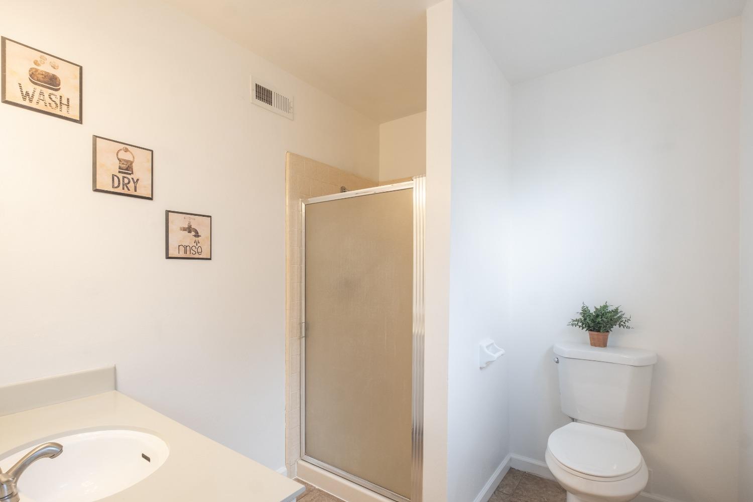 2248 Sunnyside Avenue Clovis, CA 93612 - Photo 11 of 25 a white toilet sitting next to a bathroom sink and tub