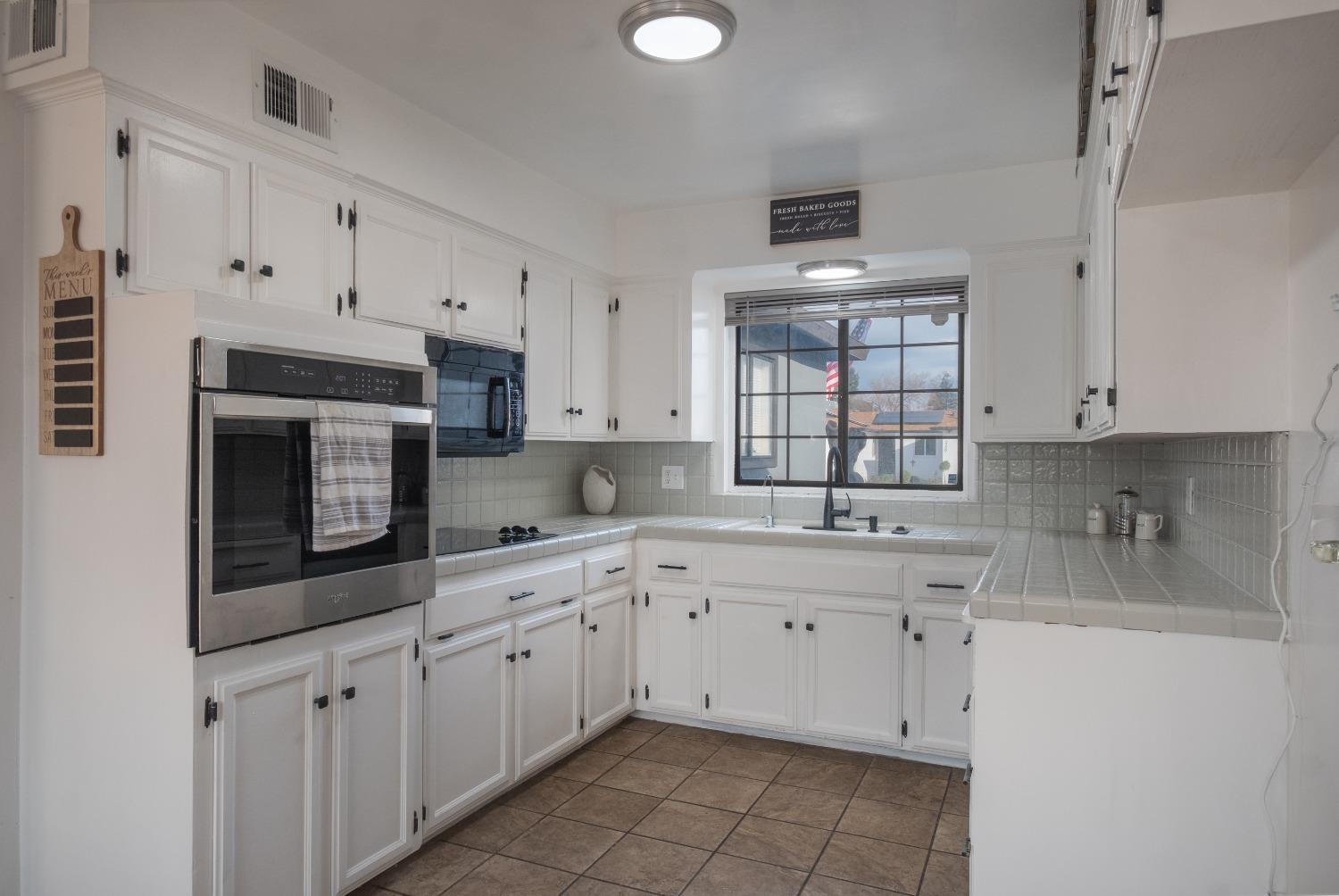 2248 Sunnyside Avenue Clovis, CA 93612 - Photo 4 of 25 a kitchen with white cabinets appliances a sink and a window