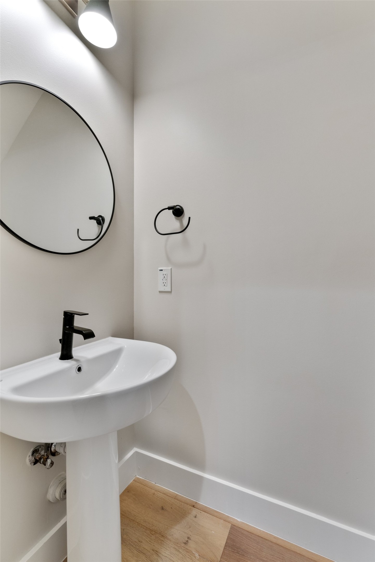 5200 Grover Avenue Austin, TX 78756 - Photo 13 of 32 Half bath downstairs. Pedestal sink with matte black faucet, complemented by a round wall-mounted mirror and coordinating towel ring