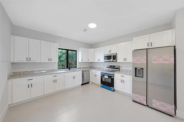 a large kitchen with white cabinets and stainless steel appliances