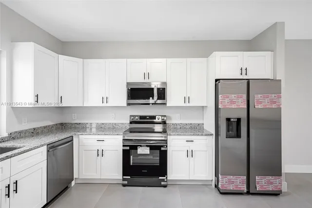 a kitchen with white cabinets and stainless steel appliances