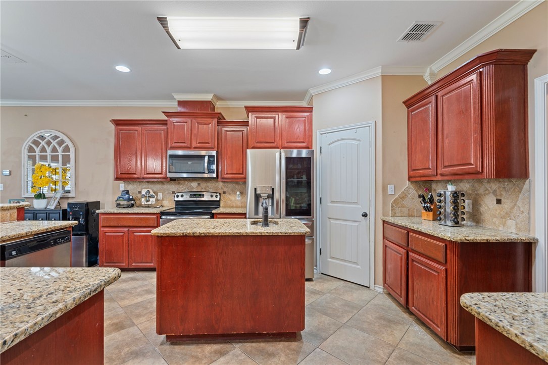 8226 Azimuth Court Corpus Christi, TX 78414 - Photo 9 of 32 a kitchen with kitchen island granite countertop wooden cabinets stainless steel appliances a sink and a counter top space