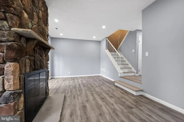 a view of an empty room with wooden floor and stairs