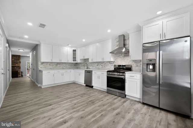 a large kitchen with stainless steel appliances granite countertop a stove a refrigerator and a sink