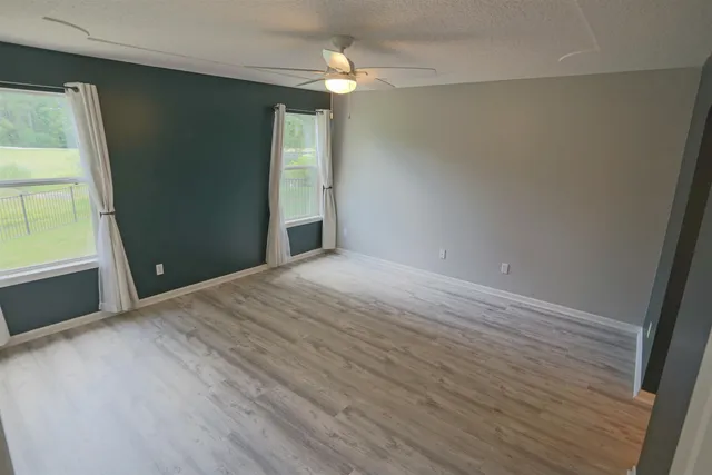 a view of empty room with wooden floor and fan