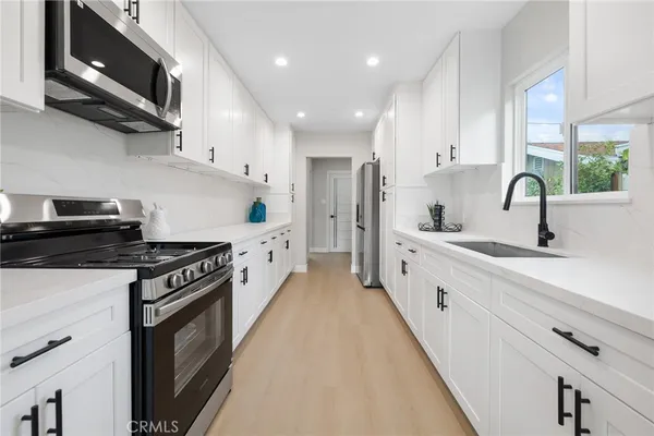 a kitchen with stainless steel appliances granite countertop a sink a stove and a refrigerator