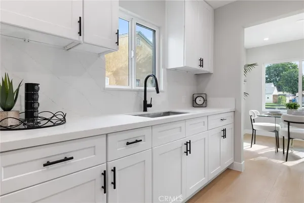 a kitchen with white cabinets and sink