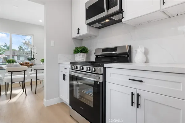 a kitchen with stainless steel appliances a stove a microwave and white cabinets