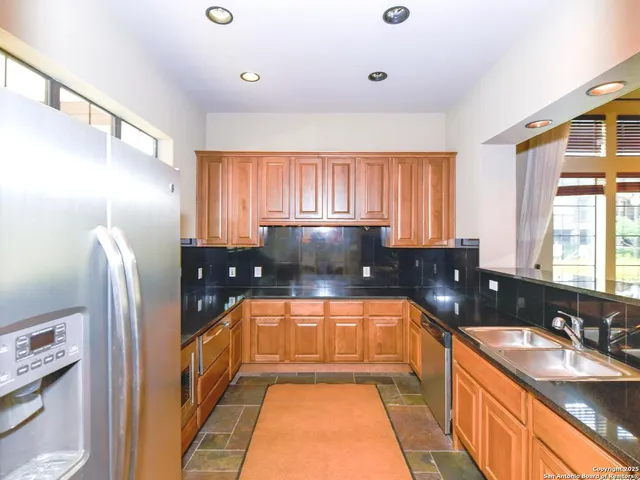 a large kitchen with granite countertop a sink and a refrigerator