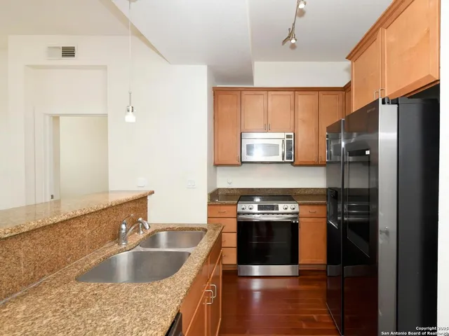 a kitchen with granite countertop a sink stove and refrigerator