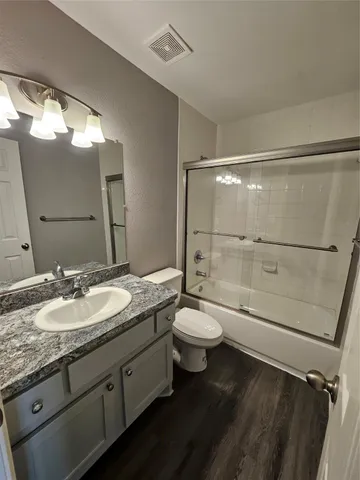 a bathroom with a granite countertop sink toilet mirror and shower
