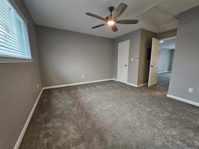 an empty room with a chandelier fan and windows