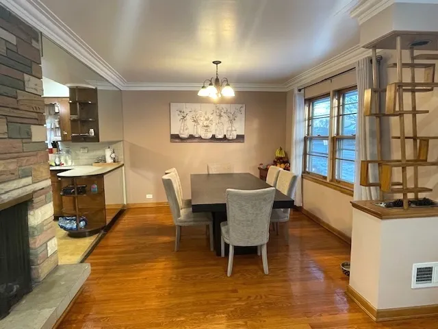 a dining room with wooden floor a chandelier a glass table and chairs