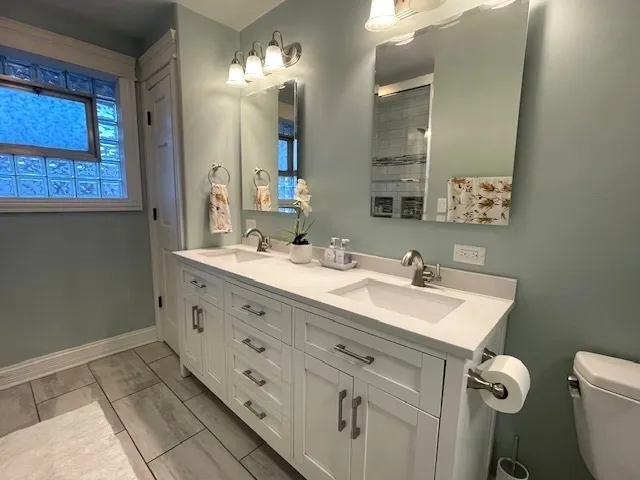a bathroom with a double vanity sink mirror and toilet
