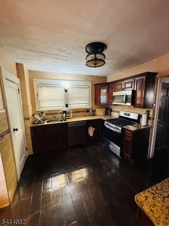 a kitchen with a chandelier appliances and wooden floor