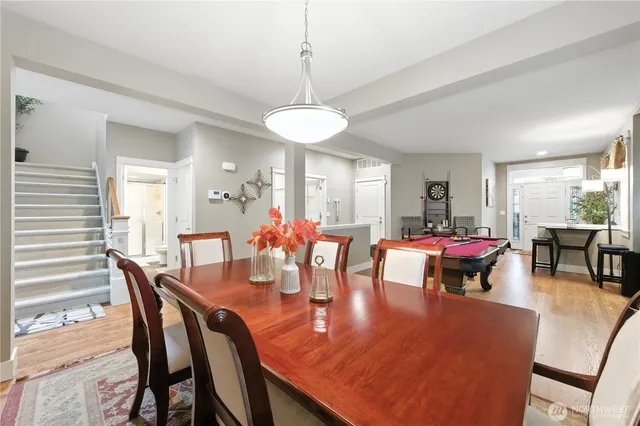 a dining room with wooden floor a chandelier a wooden table and chairs