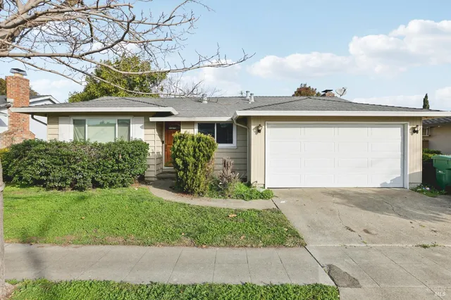 a front view of a house with a yard and potted plants