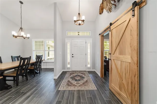 a dining room with wooden floor a chandelier a wooden table and chairs