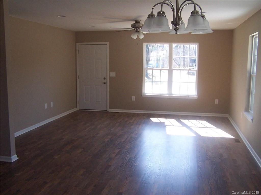 400 Rowan Mill Road Salisbury, NC 28147 - Photo 6 of 24 an empty room with wooden floor chandelier and windows