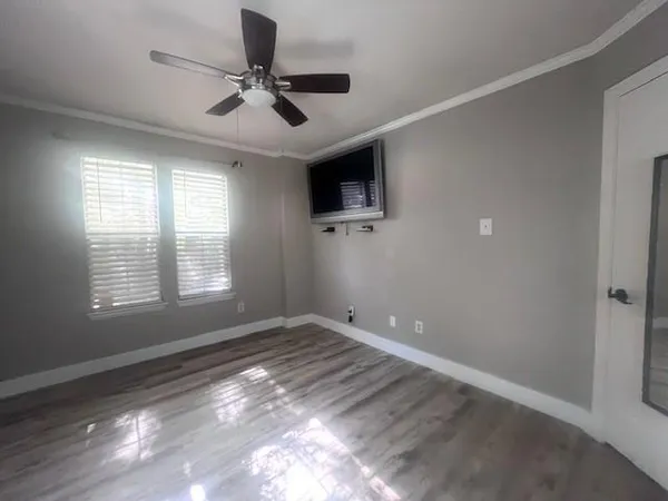 an empty room with wooden floor a ceiling fan and windows
