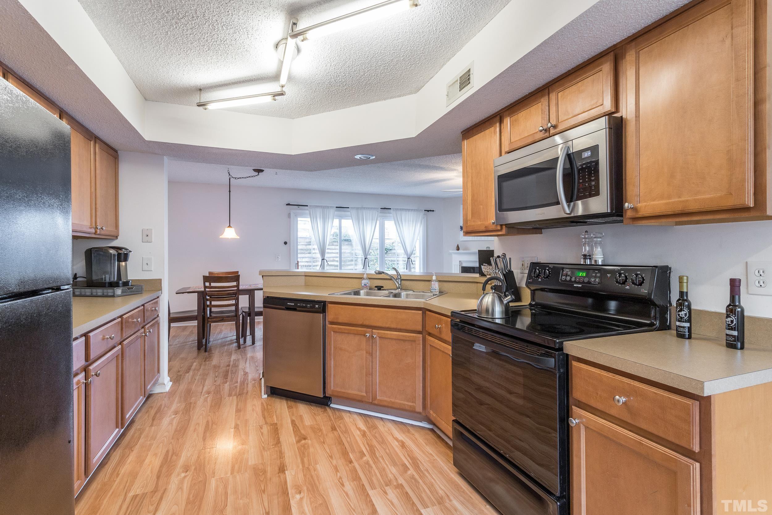 7808 Falcon Rest Circle Raleigh, NC 27615 - Photo 13 of 28 a kitchen with stainless steel appliances granite countertop wooden cabinets a stove top oven a sink and dishwasher a kitchen island with wooden floor
