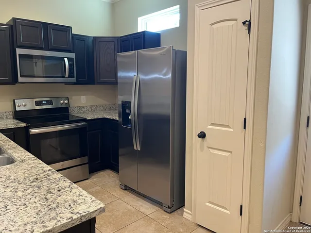 a kitchen with stainless steel appliances granite countertop a refrigerator and a stove top oven