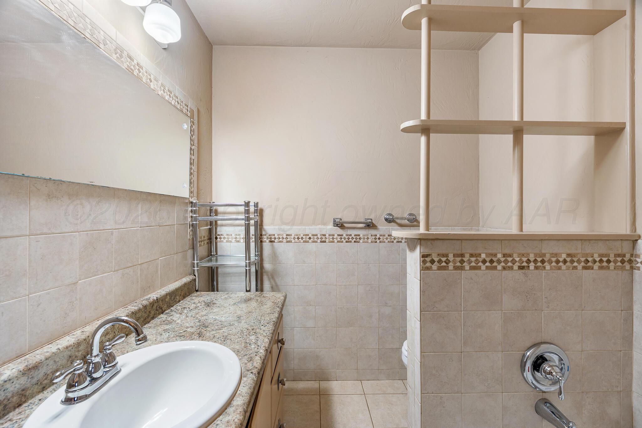 710 North Roberts Street Amarillo, TX 79107 - Photo 12 of 20 a bathroom with a granite countertop sink a mirror and shower