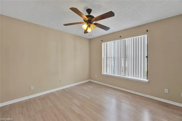 an empty room with wooden floor fan and windows