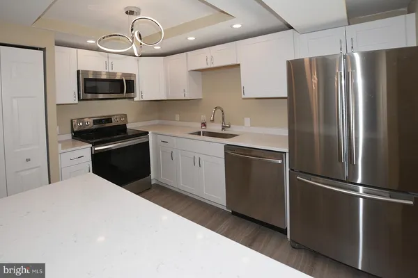 a kitchen with stainless steel appliances granite countertop a refrigerator a stove top oven a sink and dishwasher
