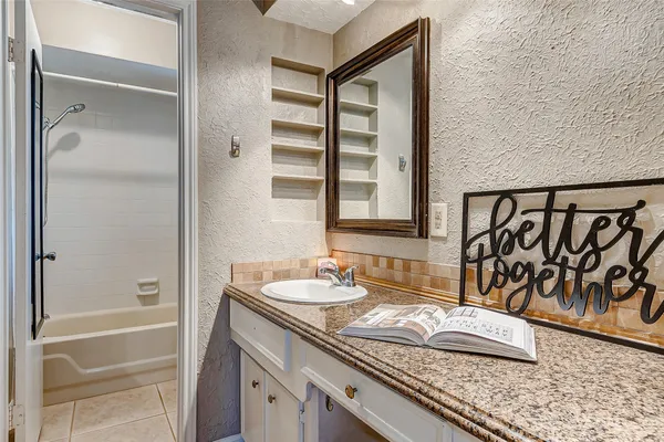 a bathroom with a granite countertop sink and a mirror
