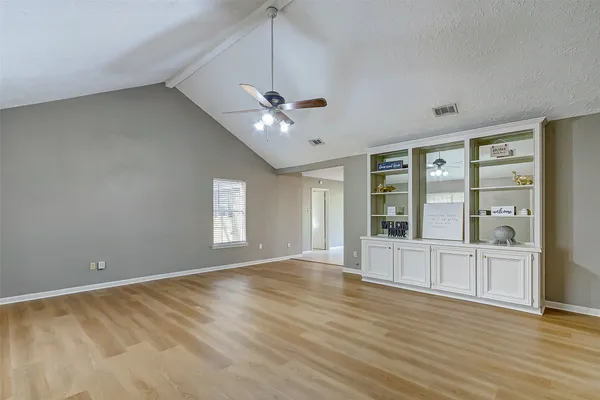 a view of an empty room with a window and wooden floor