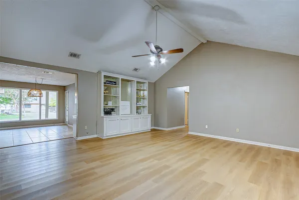 a view of an empty room with a window and wooden floor