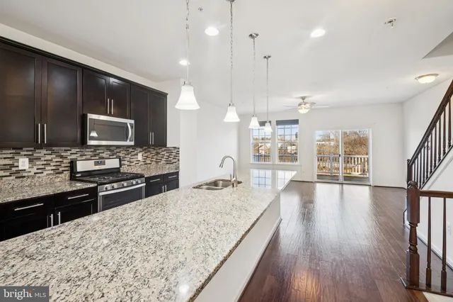 a large kitchen with granite countertop a large counter top stainless steel appliances and windows