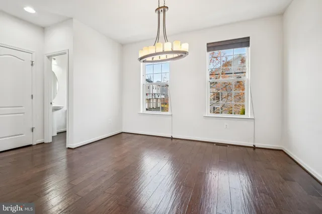 an empty room with wooden floor chandelier and windows