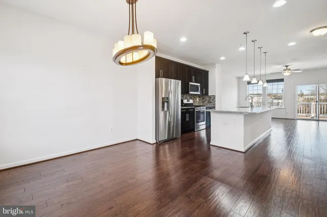 a view of kitchen with stainless steel appliances granite countertop a stove top oven a refrigerator a sink and a wooden floor