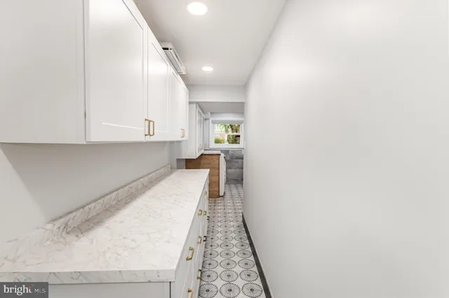 a hallway with white cabinets and wooden floor