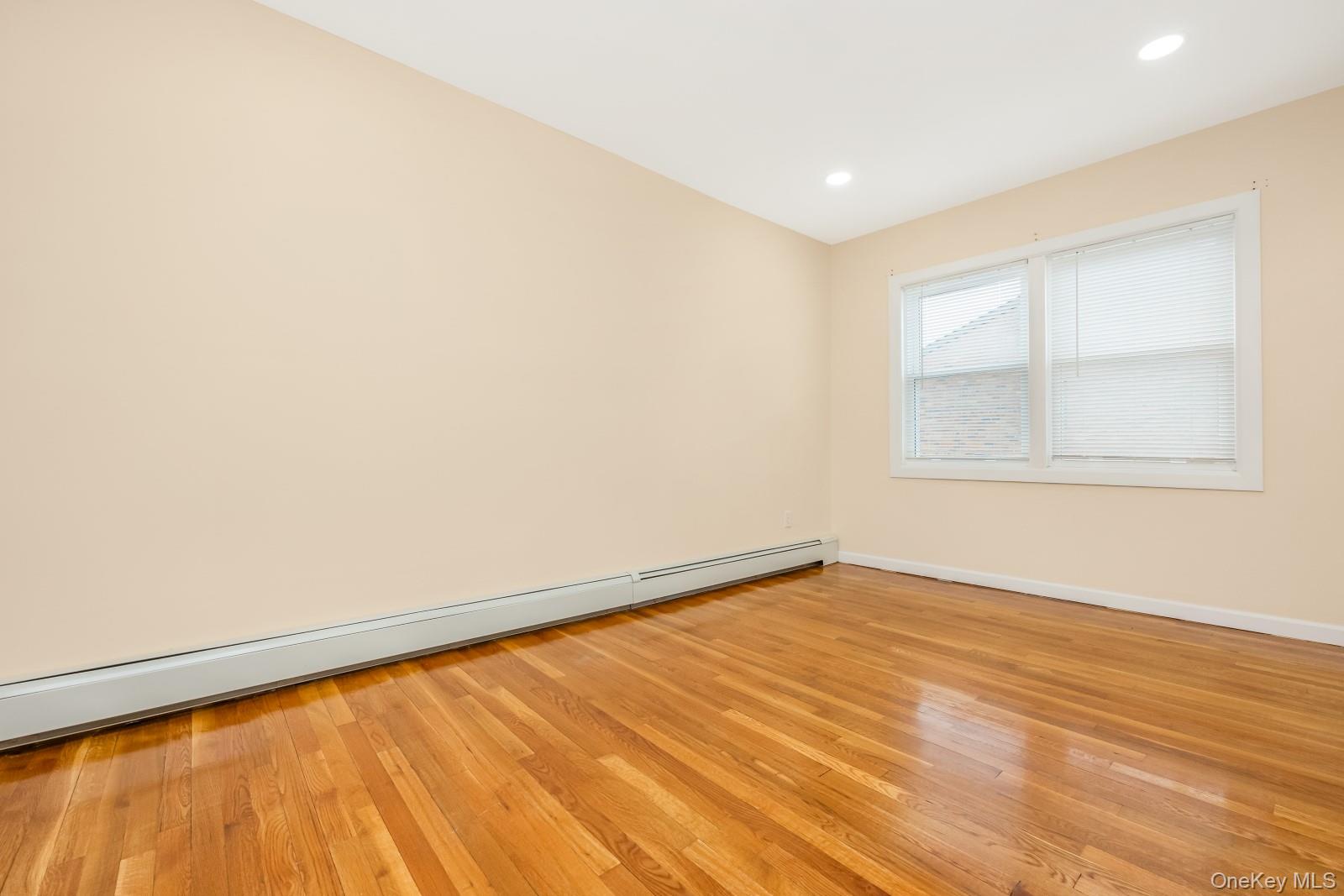69-05 61st Road Queens, NY 11379 - Photo 21 of 31 an empty room with wooden floor and windows