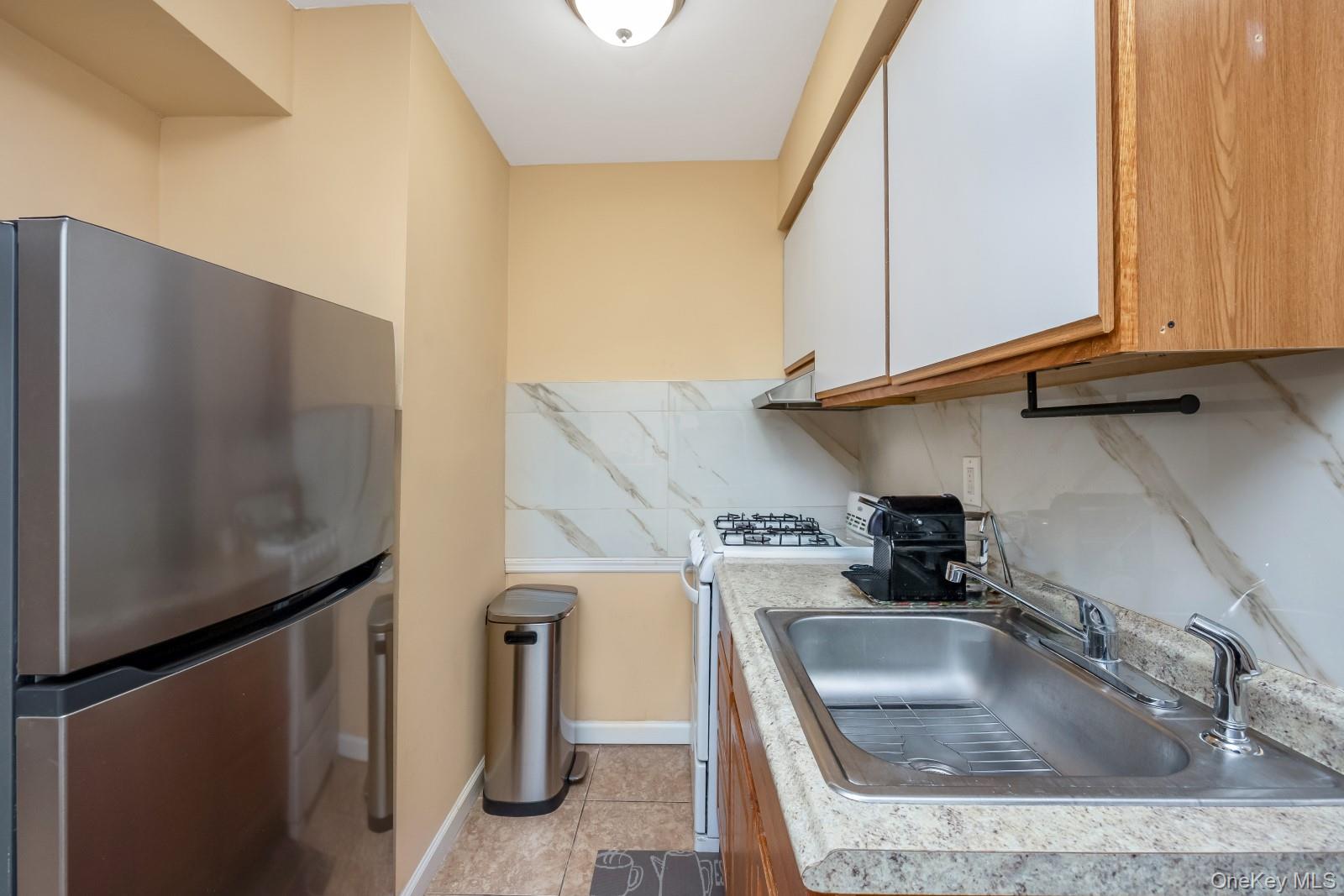 69-05 61st Road Queens, NY 11379 - Photo 23 of 31 a kitchen with stainless steel appliances granite countertop a sink a stove and a refrigerator with wooden floor