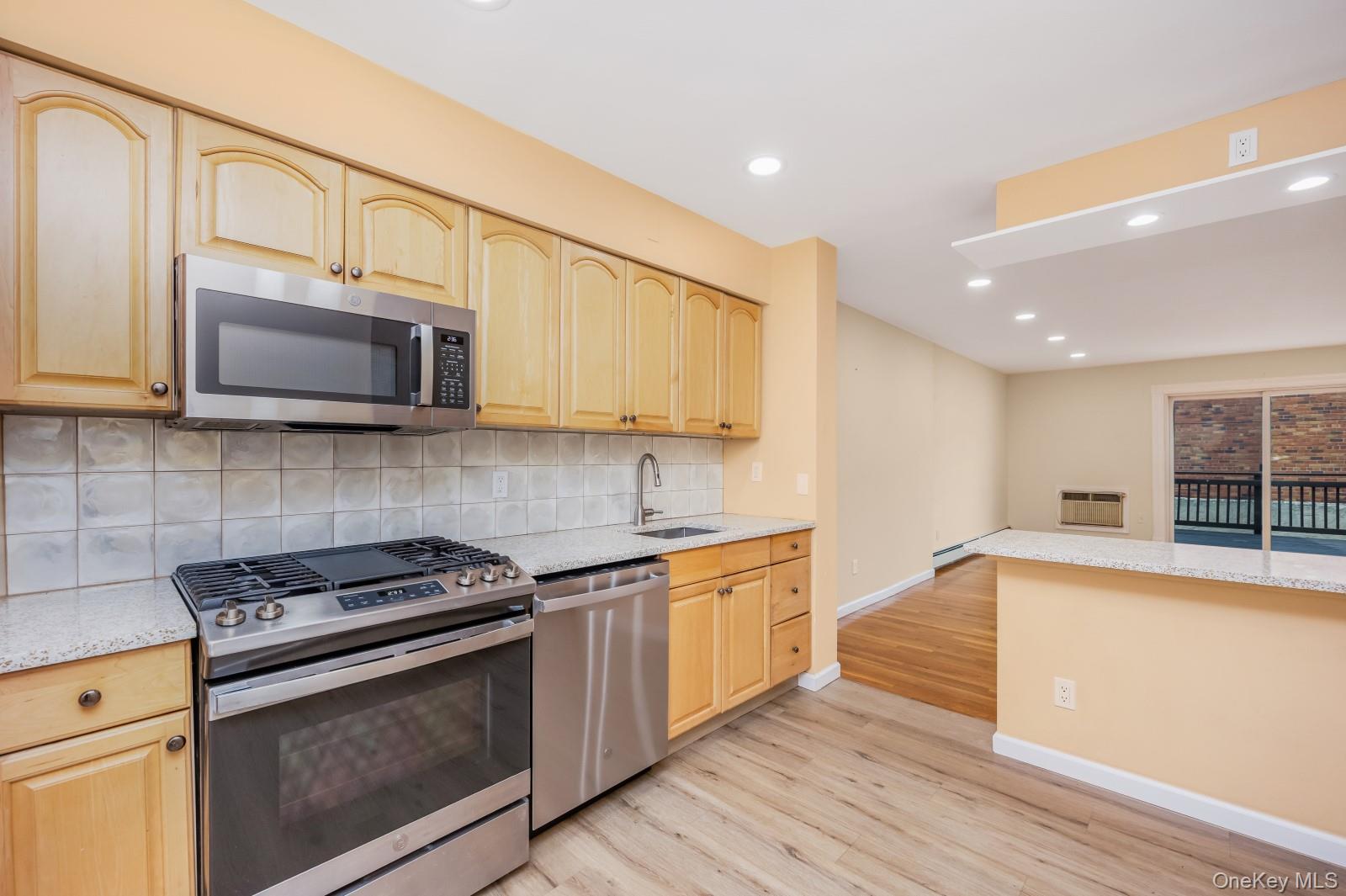 69-05 61st Road Queens, NY 11379 - Photo 5 of 31 a kitchen with stainless steel appliances granite countertop a sink a stove top oven and wooden floors