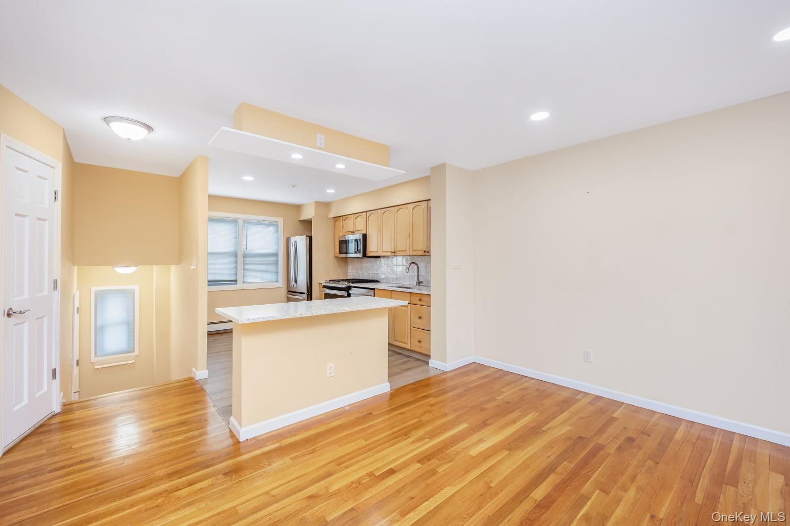 69-05 61st Road Queens, NY 11379 - Photo 8 of 31 a open kitchen with white cabinets and wooden floor