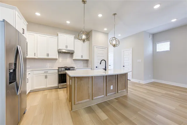 a large kitchen with cabinets wooden floor and stainless steel appliances