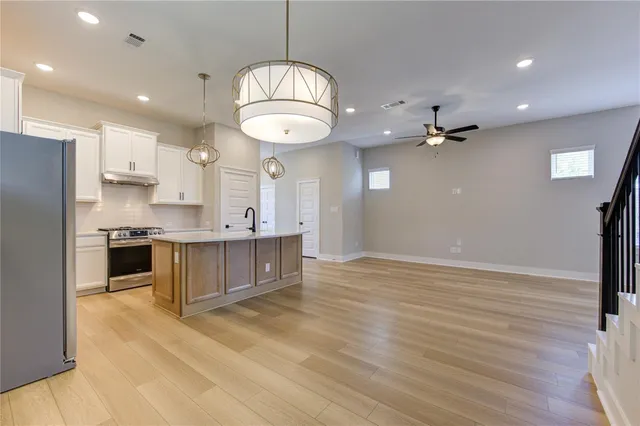 a large kitchen with kitchen island stainless steel appliances sink cabinets and wooden floor
