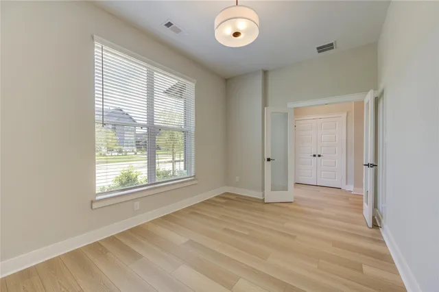 a view of an empty room with a window and wooden floor