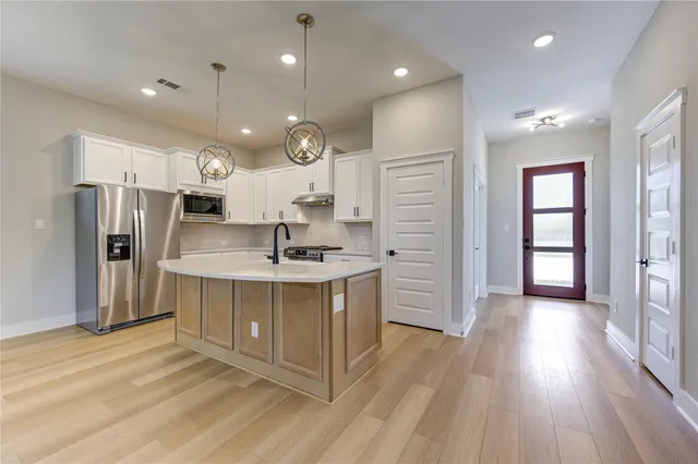 a kitchen with stainless steel appliances granite countertop a sink and a refrigerator