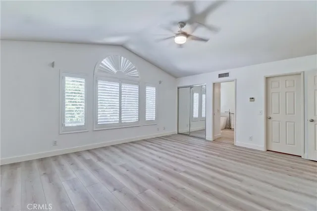 an empty room with wooden floor fan and windows