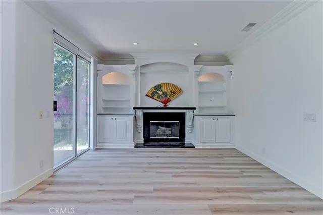 an empty room with wooden floor a fireplace and a window