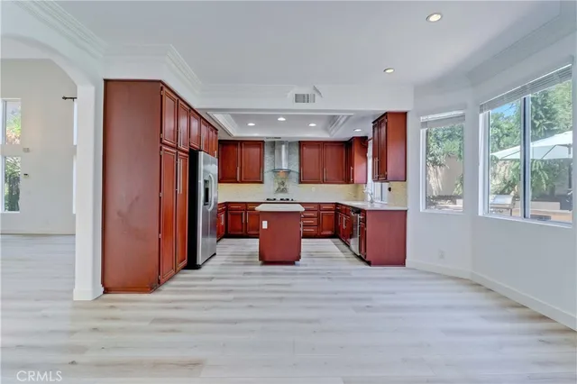 a open kitchen with kitchen island granite countertop wooden floors and a sink